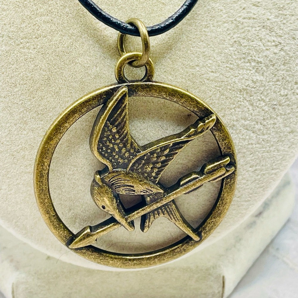 Gold Tone Hunger Games Mockingjay Pendant Necklace on a Black Cord. 18 inches